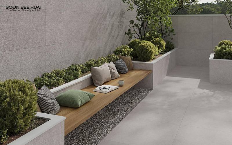 Outdoor patio featuring textured grey stone-look tiles and wooden bench.