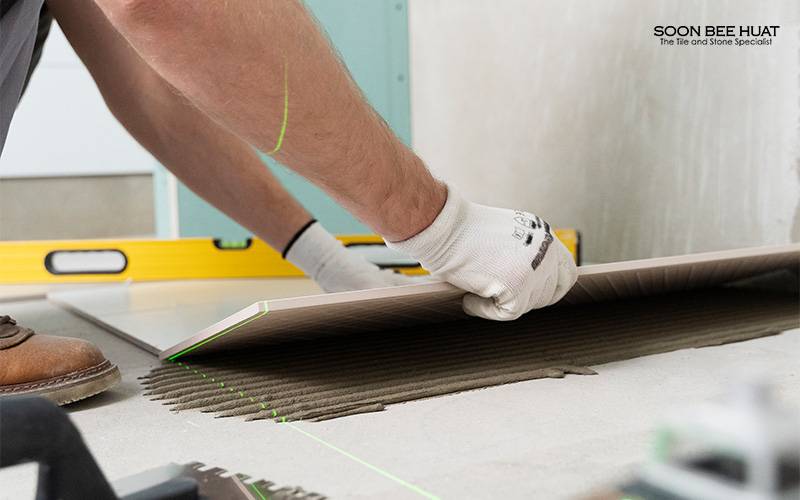 A worker installing new tiles onto a floor.