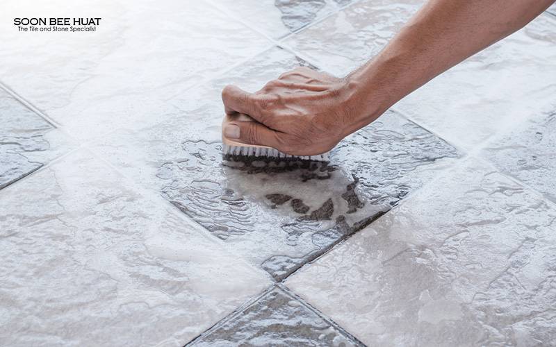 A person cleaning low-maintenance tiles with a brush.